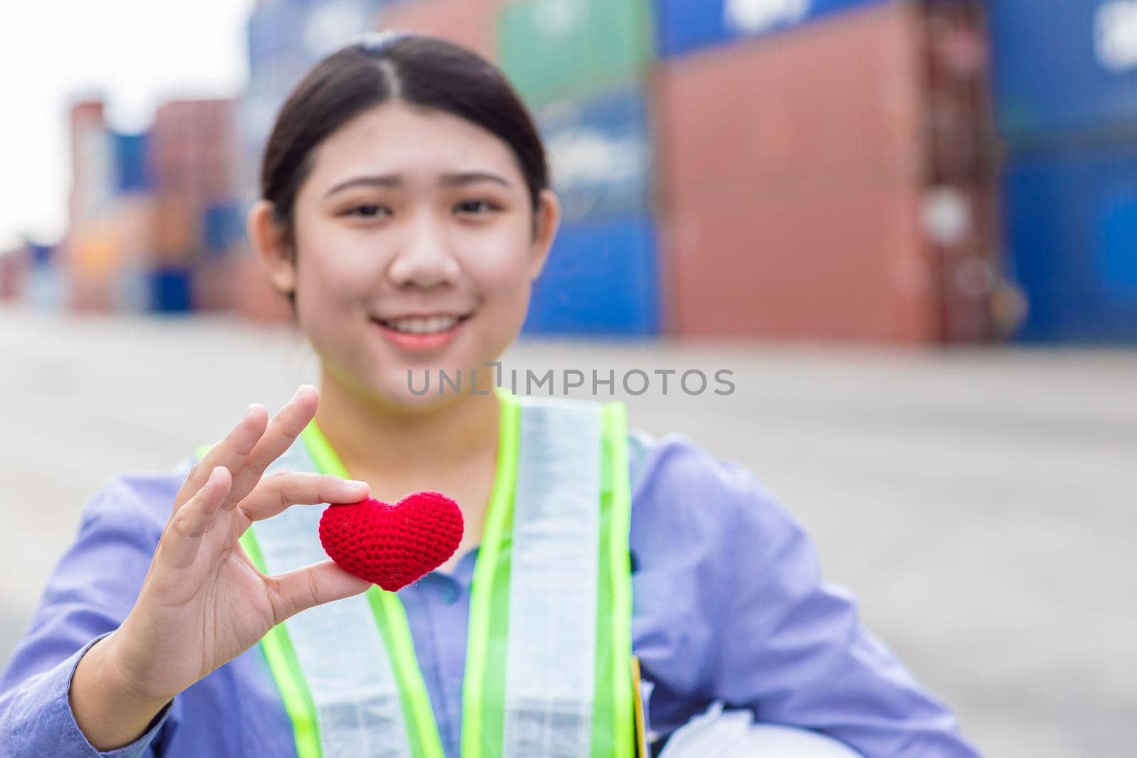 Girl teen worker in cargo container shipping port working with heart and good service mind concept. selective focus at red heart. by qualitystocks