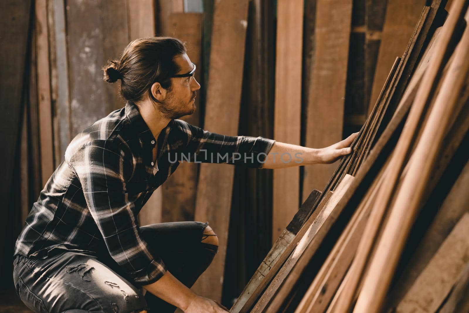 Carpenter man working in furniture wood workshop, selecting wooden board.