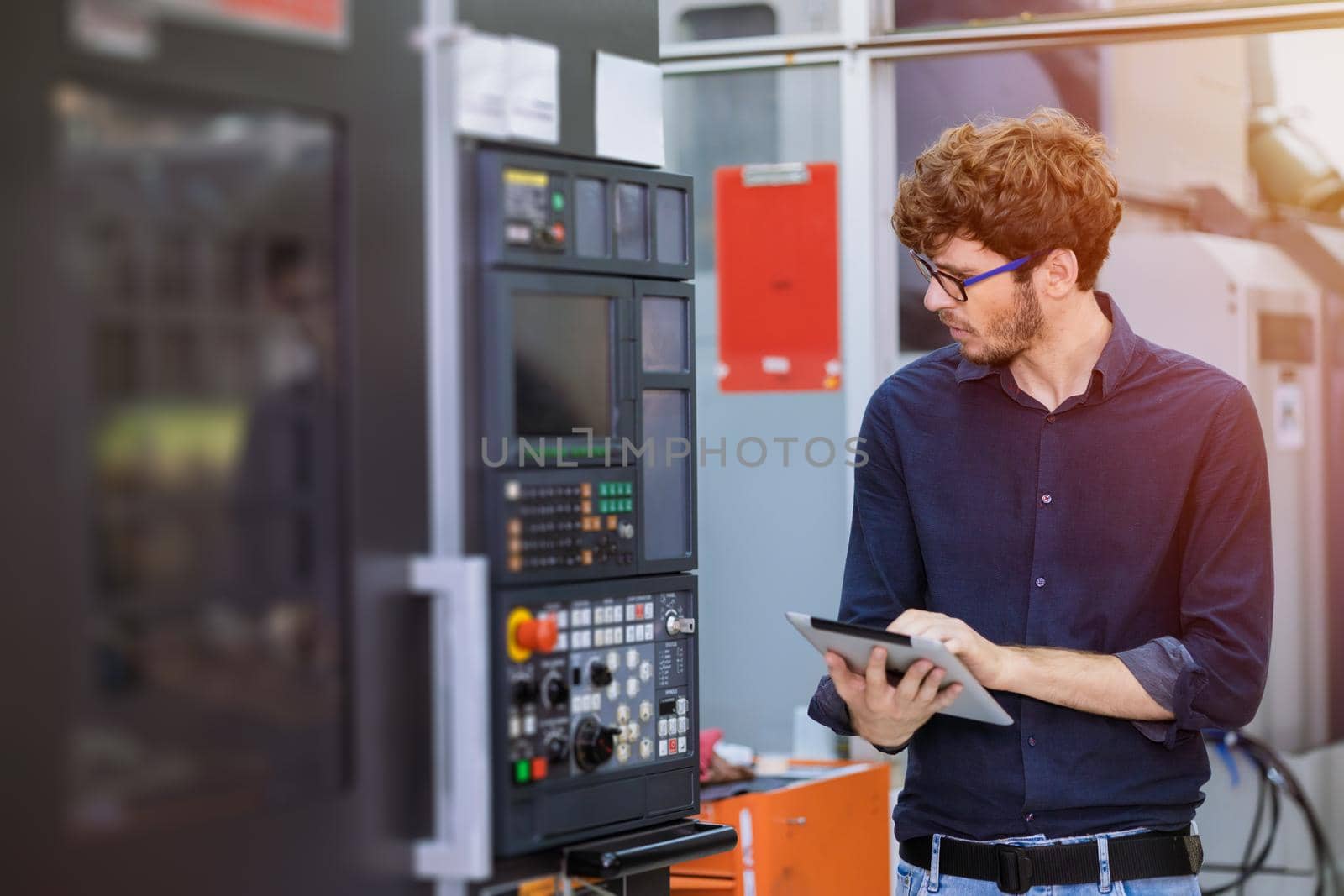 Young American engineer worker working programing heavy industrial machine in factory. employee looking and control CNC machine in production line. by qualitystocks