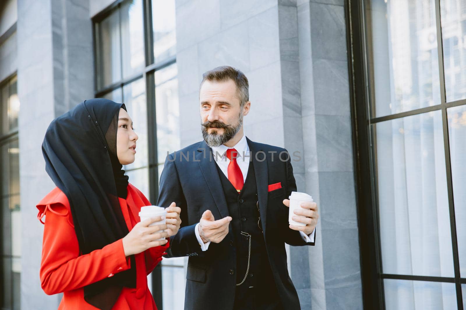 Arab Muslim business people man and woman morning coffee walking talking together by qualitystocks