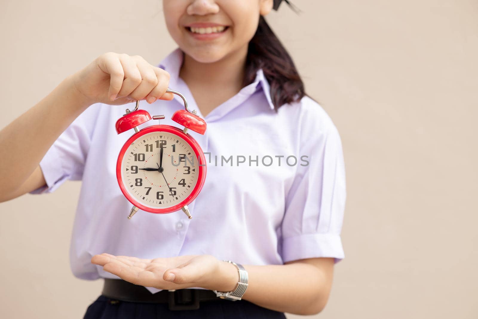 Asian Student handle alarm clock for education times or go to school happy smile. by qualitystocks
