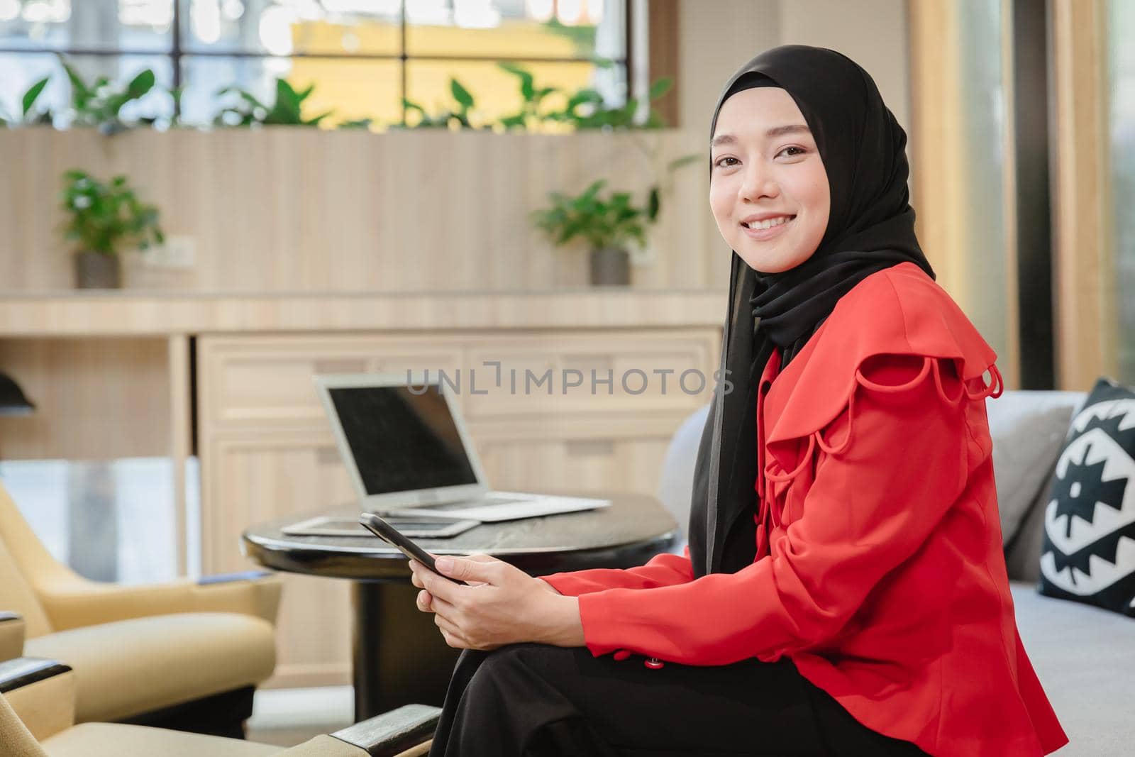 Arab Muslim businesswoman girl smiling sitting portrait in business office,Islam working woman concept by qualitystocks