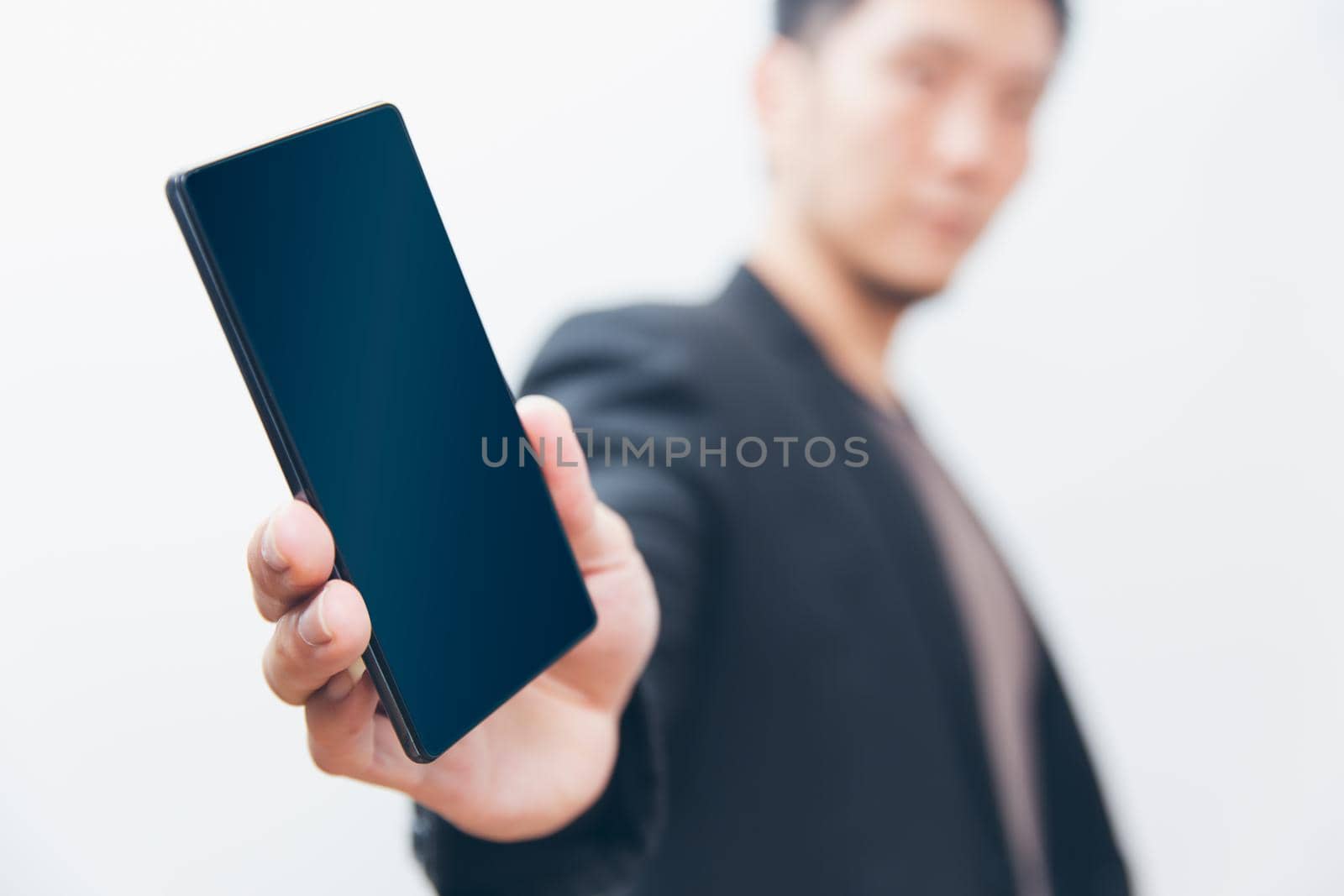 Business man handing giving out a cell phone show blank screen with white background shallow depth of field.