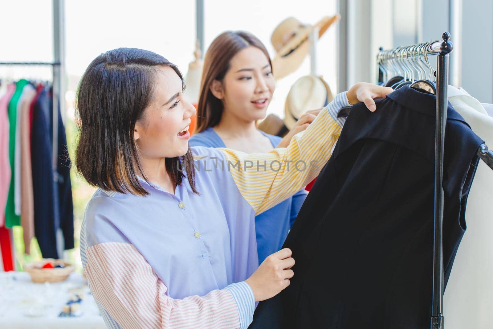 Asian girls teen enjoy shopping to select new cloth with friend in fashion shop like black color cloth.