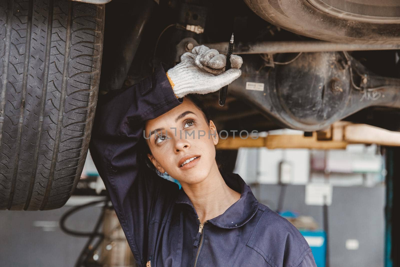 Tired woman staff worker hard work in hot danger place wiping away sweat working in auto car service garage. by qualitystocks