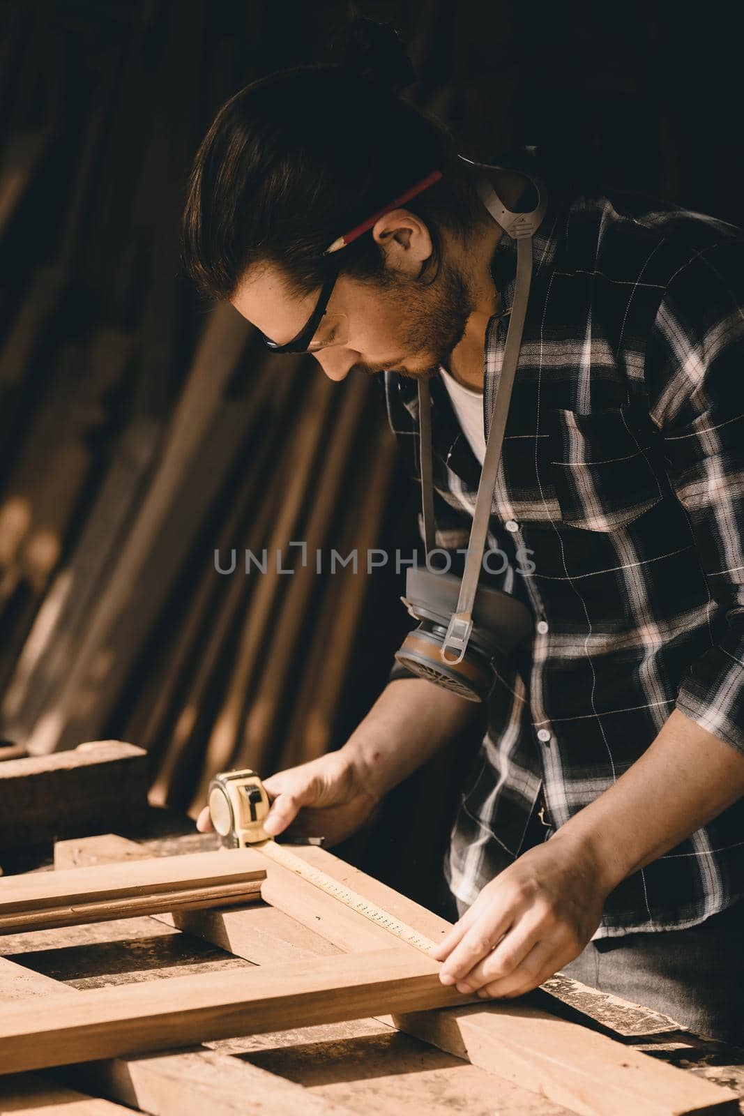 Carpenter man attend to making masterpiece woodworks handcrafted furniture fine measure in wood workshop, Vertical shot.