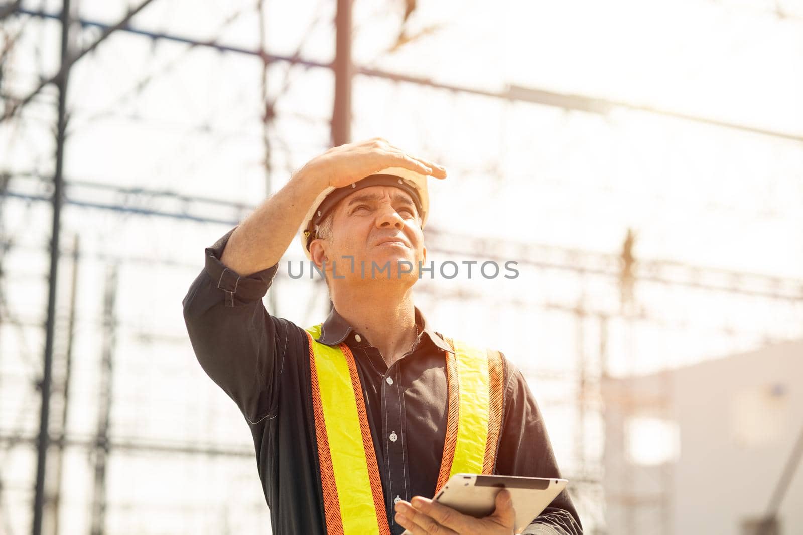 Foreman builder engineer worker looking at large building construction site sunny day hard work.