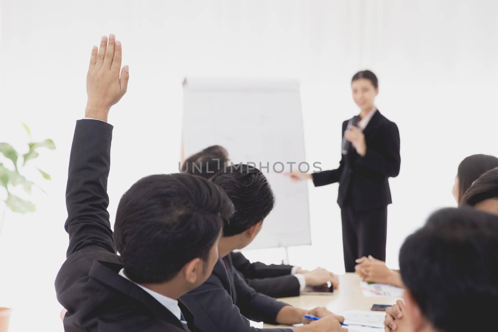 Business meeting speech request concept. Businessman rising hand for asking question to speaker in company meeting room.