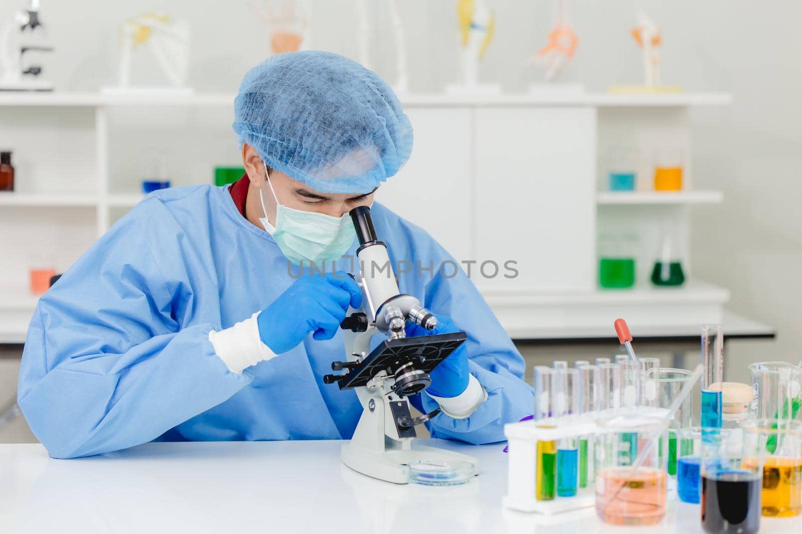 Scientist Doctor in research lab working observer dangerous virus with microscope.