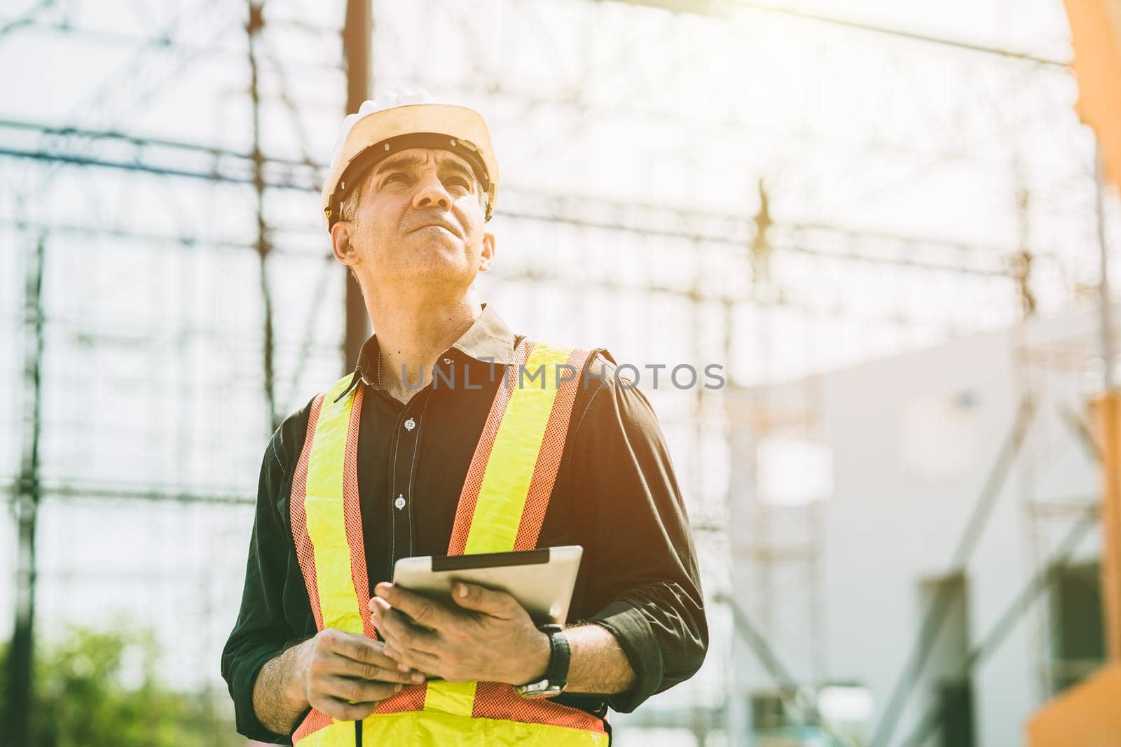 Foreman builder engineer worker looking at large building construction site sunny day hard work. by qualitystocks