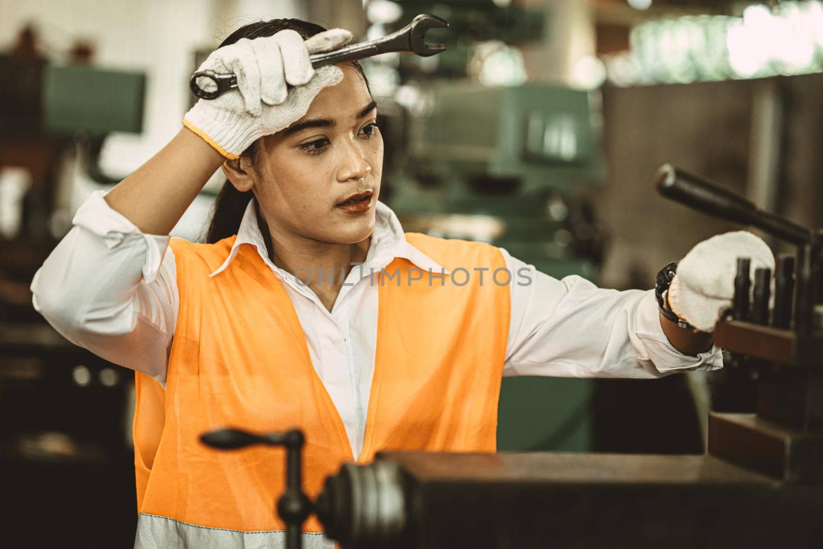 Tired woman worker Asian labor hard work in hot factory wiping away sweat working with metal machine. by qualitystocks