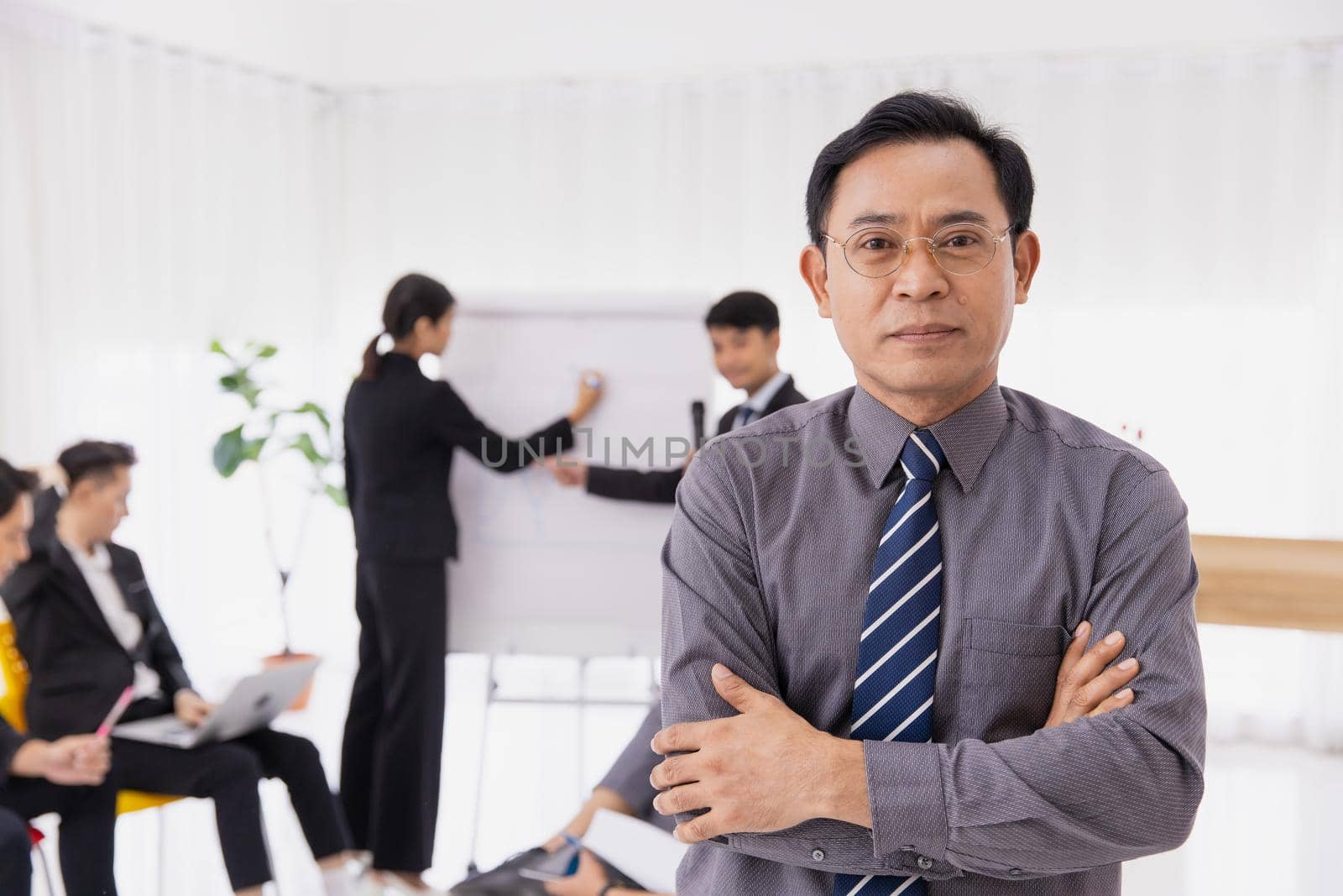 Portrait Asian adult smart businessman confident arm crossed. Business owner male standing with office worker planning management meeting.