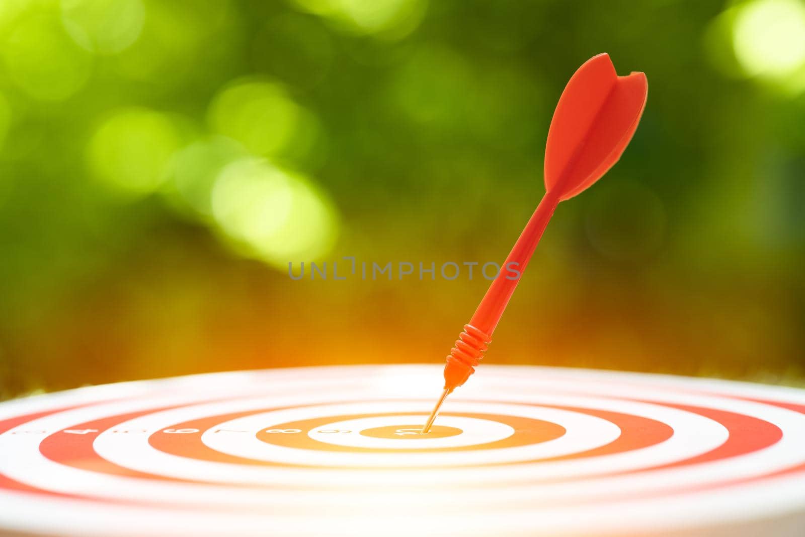 Close up red dart arrow hit the center target highest score of dartboard. Business management and planing to success go winner goal concept. by qualitystocks