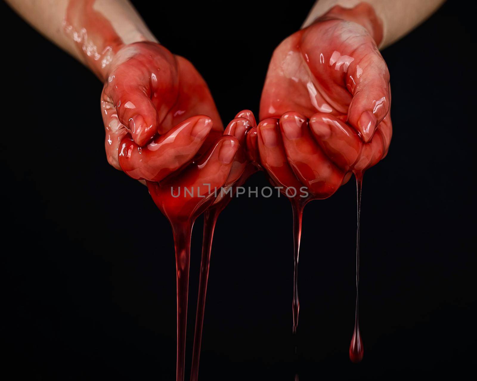 Women's hands in a viscous red liquid similar to blood