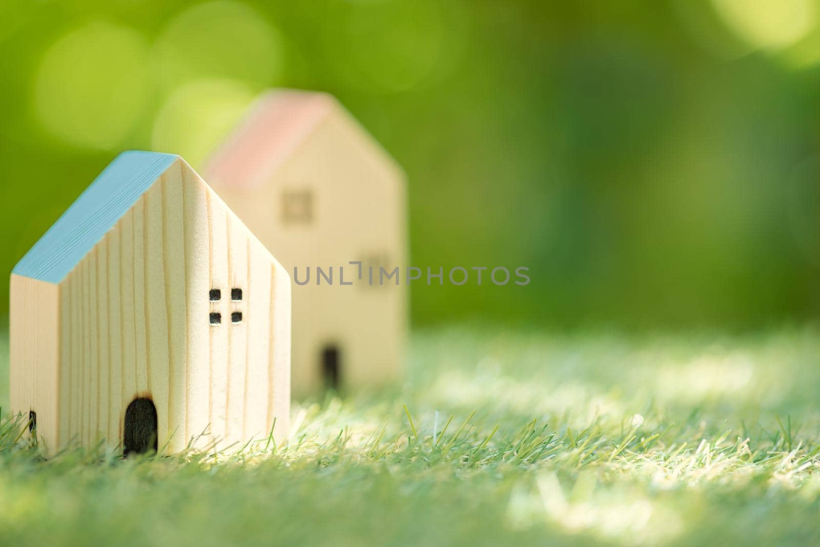 Small wooden home in green nature background for eco house village community postcard banner image. by qualitystocks