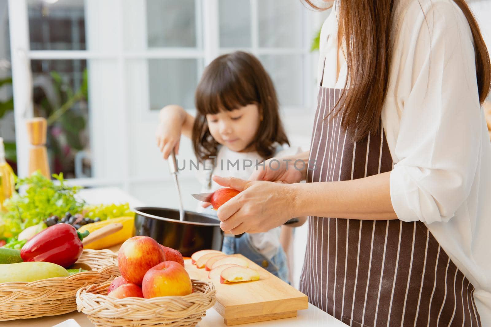 Closeup child girls playing innocently in the kitchen with mother cooking at home.