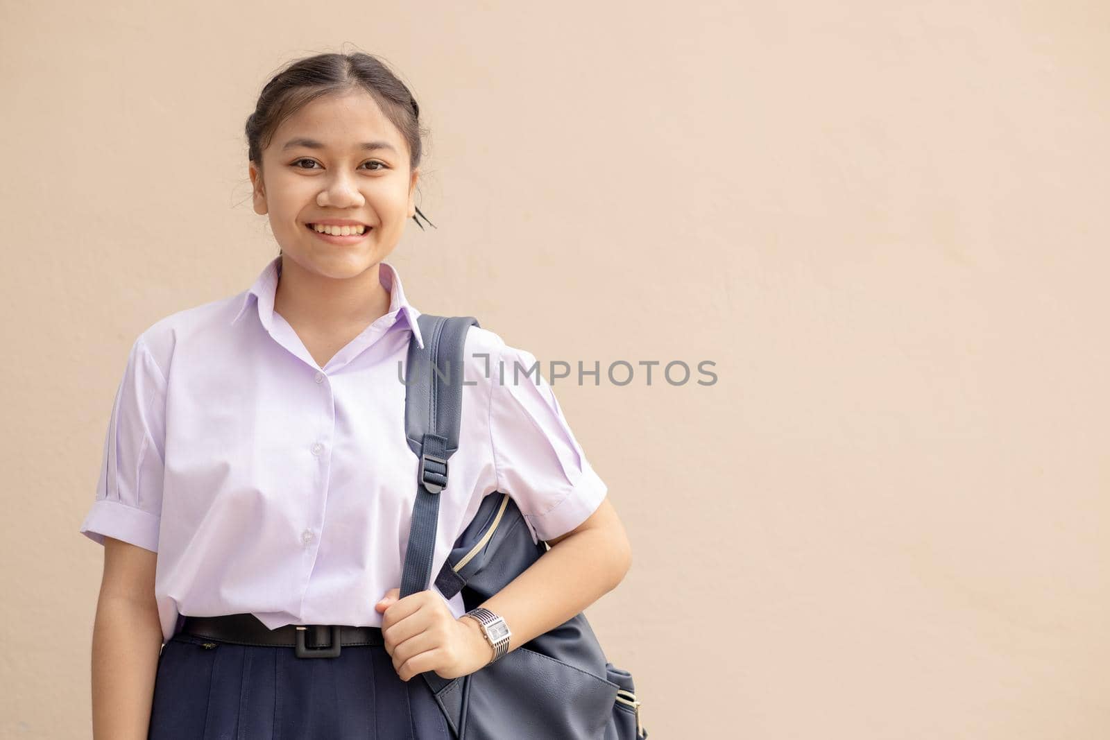 Asian School girl teen cute student in uniform happy smile with bag looking camera with space for text. by qualitystocks