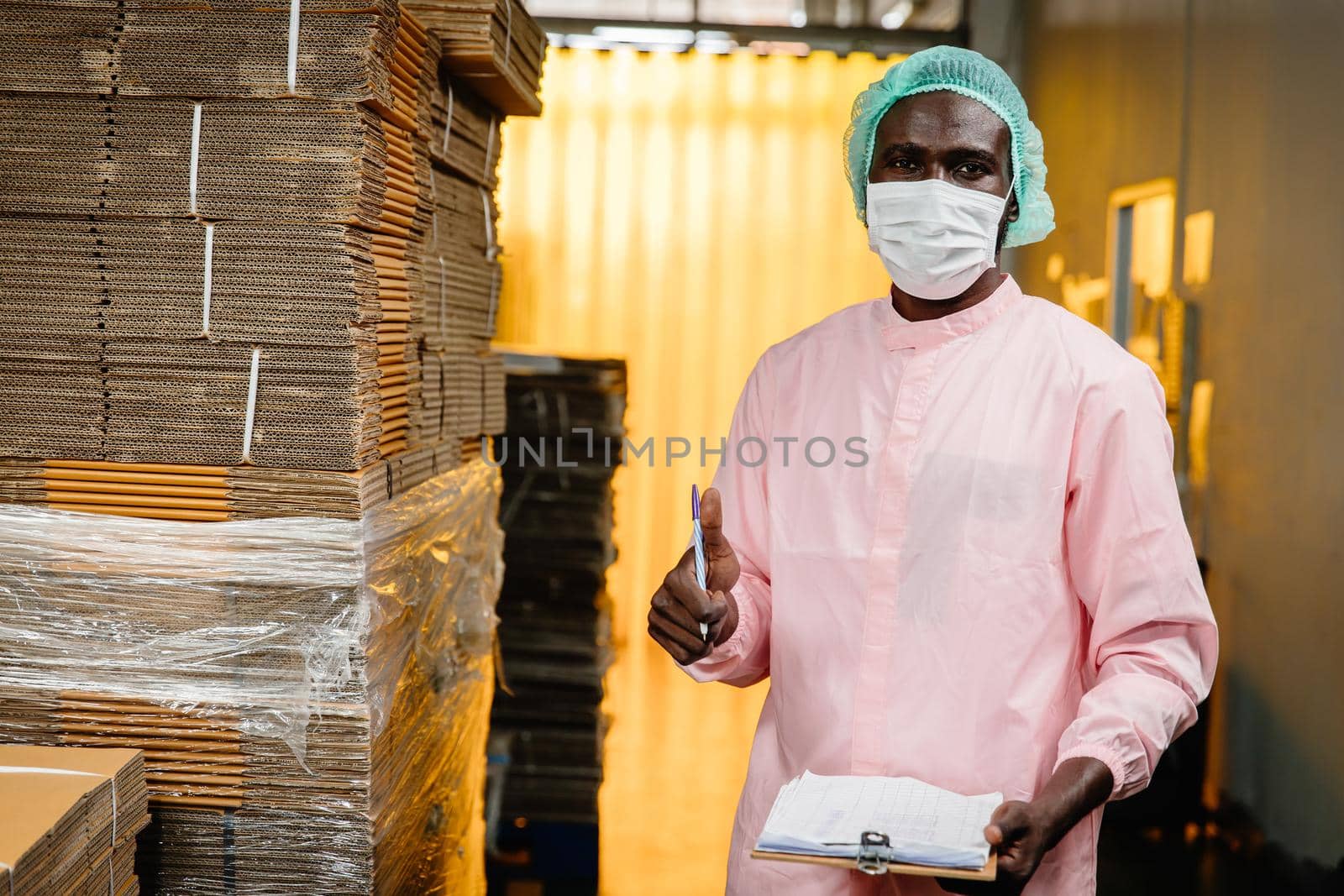 Black worker working in factory to check counting stock inventory in production warehouse standing thumbs up for good job and welfare.
