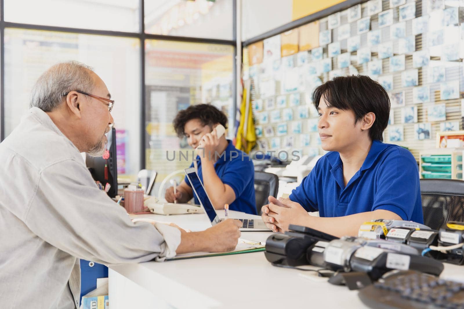 Customer sign contract document to apply membership and talk to reception male staff at counter service in business shop.