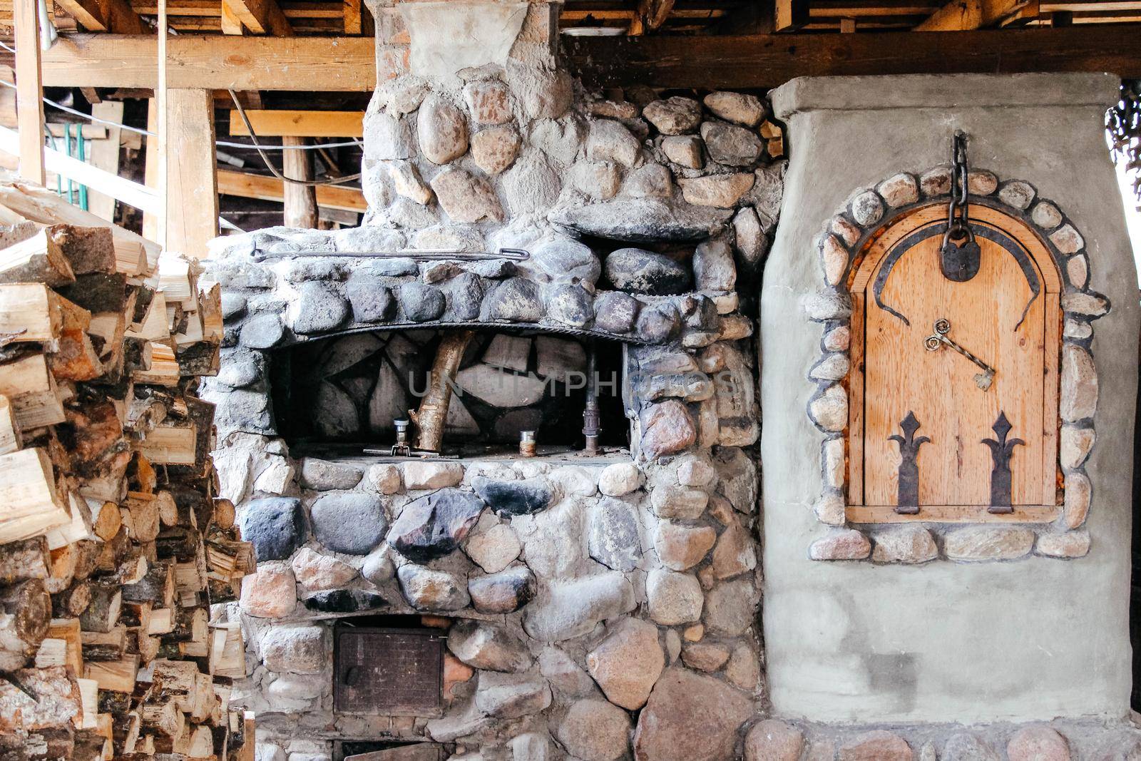 Old Slavic village street cooking stove with stack of firewood nearby . High quality photo