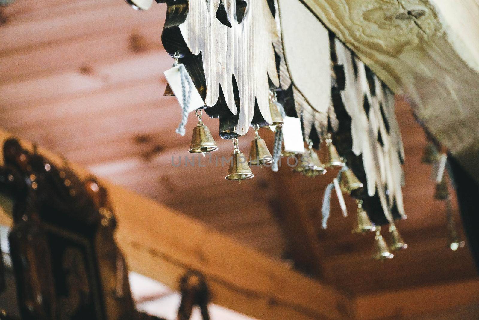 Steel bells hang indoors under a wooden ceiling. High quality photo