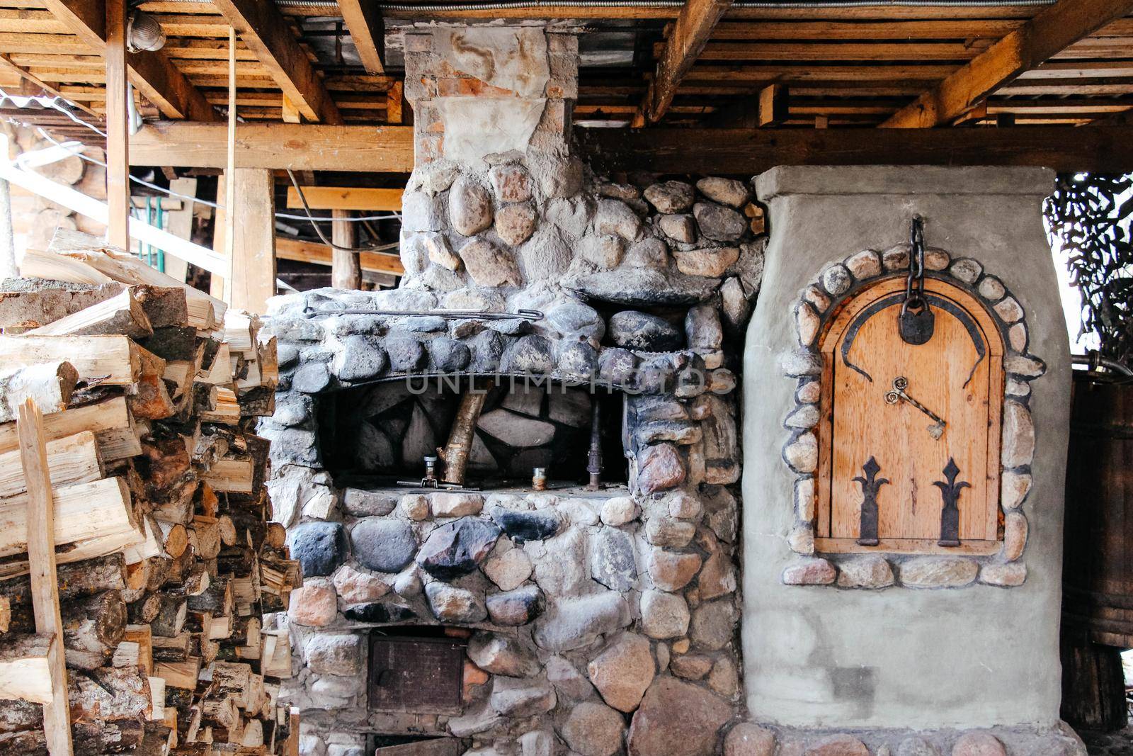 Old Slavic village street cooking stove with stack of firewood nearby . High quality photo