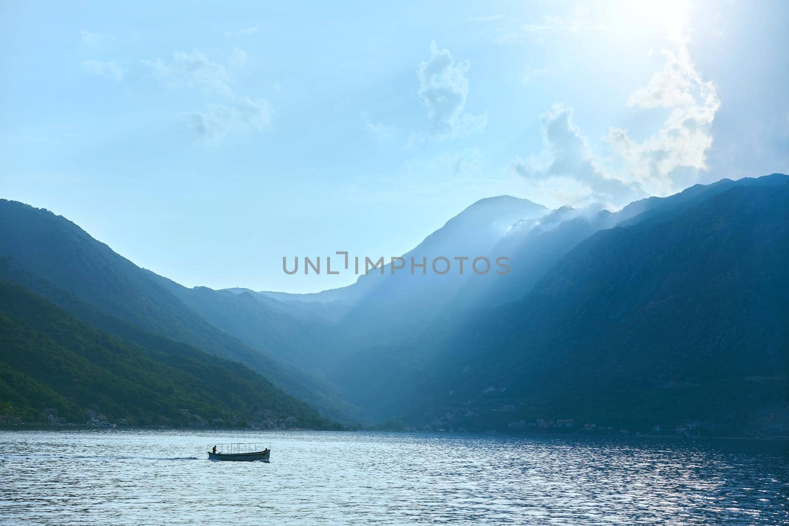 A boat with fishermen floats on the sea against the backdrop of a mountainous landscape in the Adriatic Sea in Montenegro.