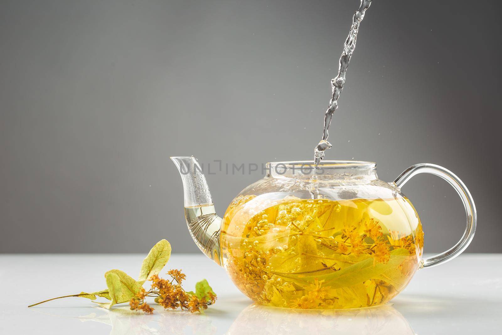 Pouring hot water into teapot with linden tea by Syvanych