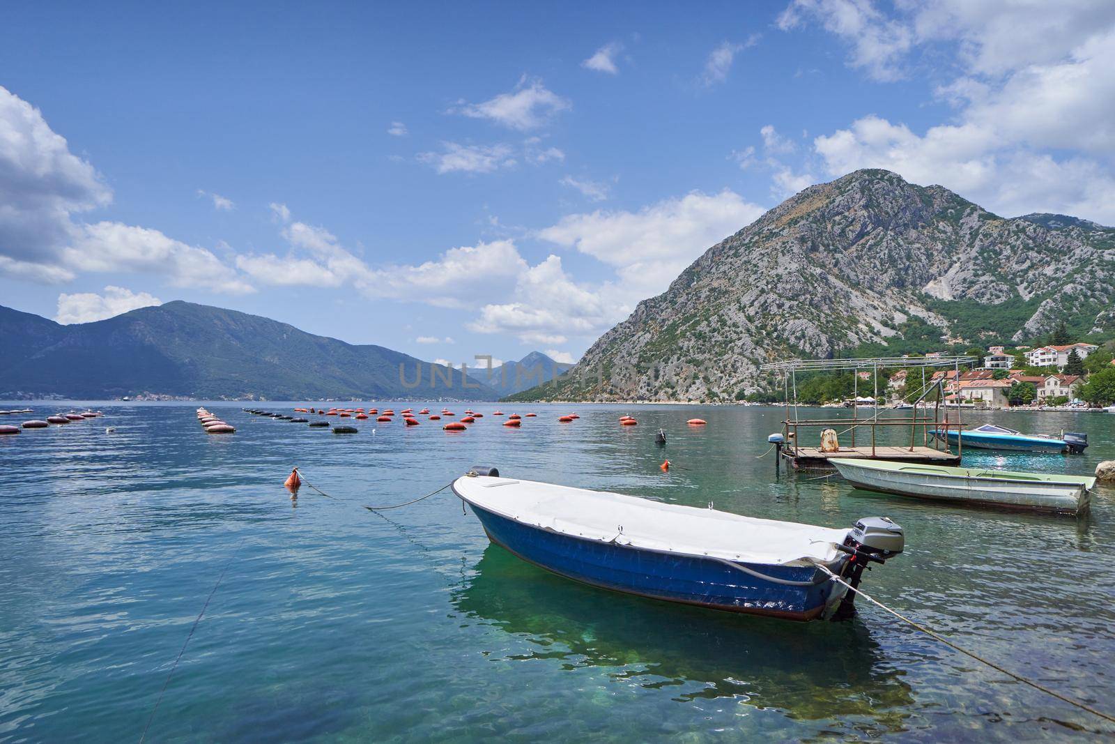 Fishing boat on the background of oyster farms and mountains in the Adiatic Sea, Montenegro.