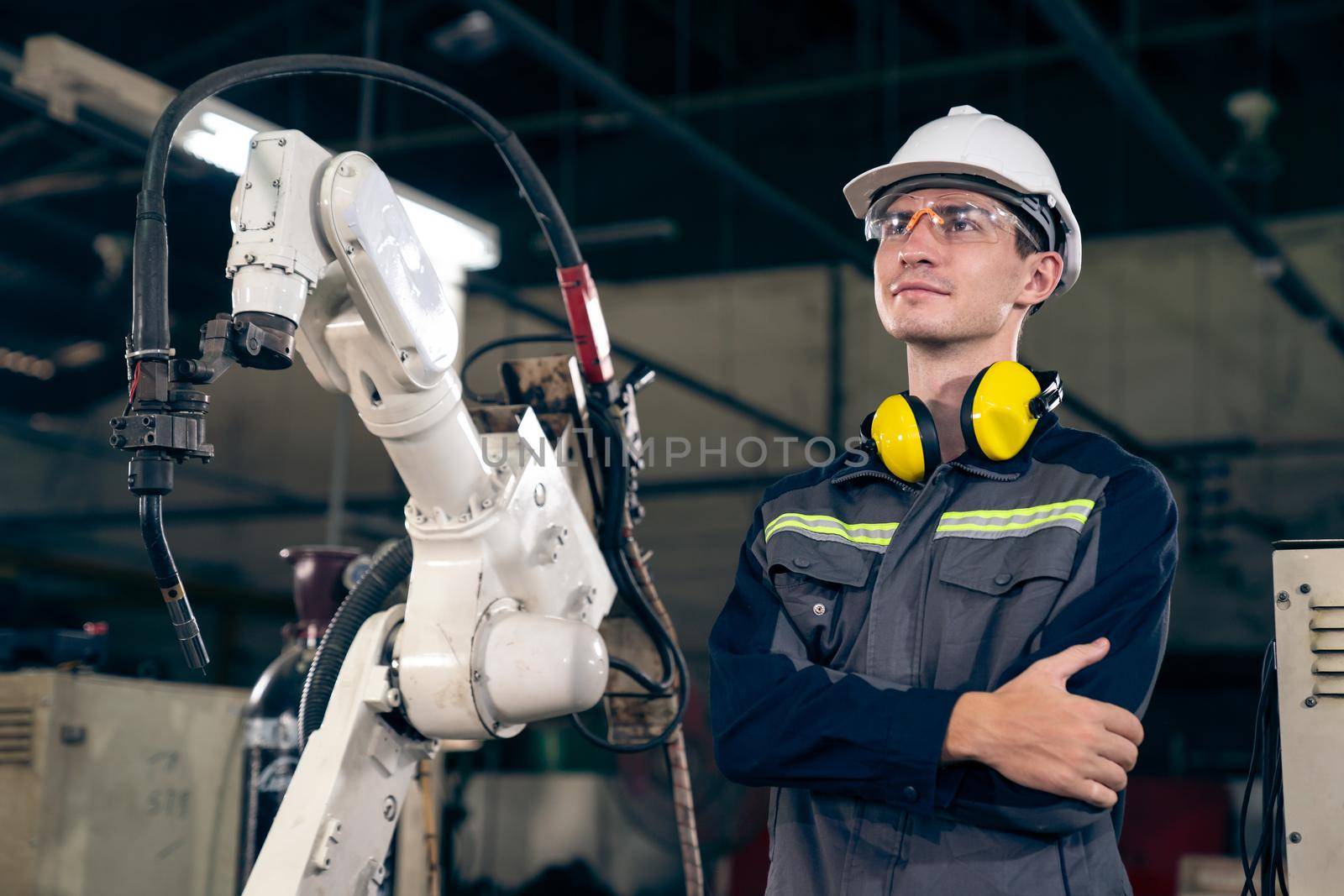 Young factory worker working with adept robotic arm in a workshop . Industry robot programming software for automated manufacturing technology .