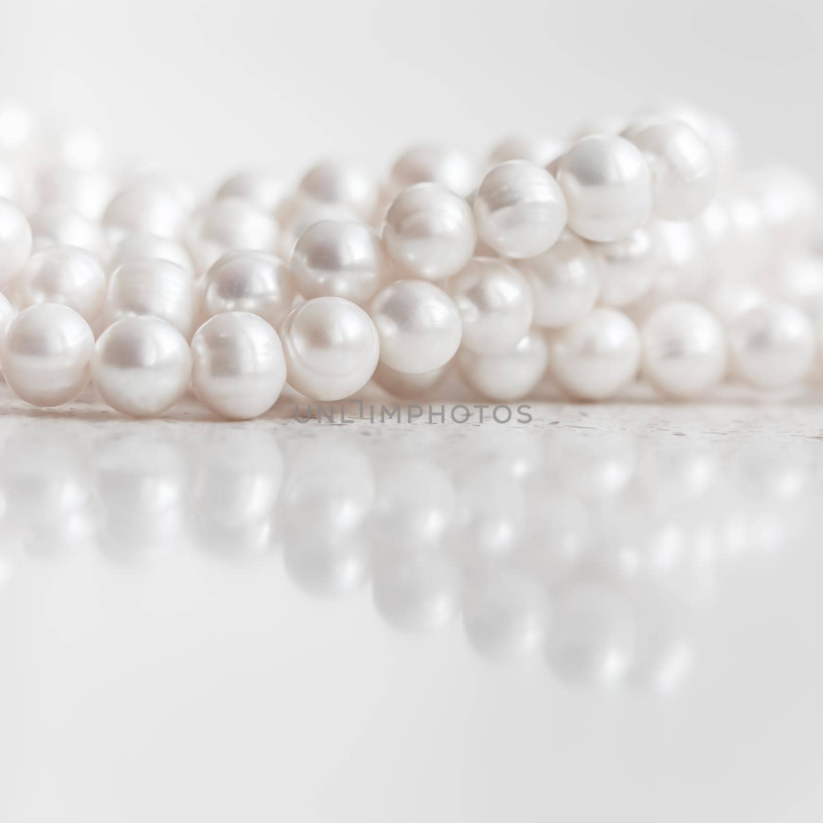 Nature white string of pearls on marble background in soft focus, with highlights