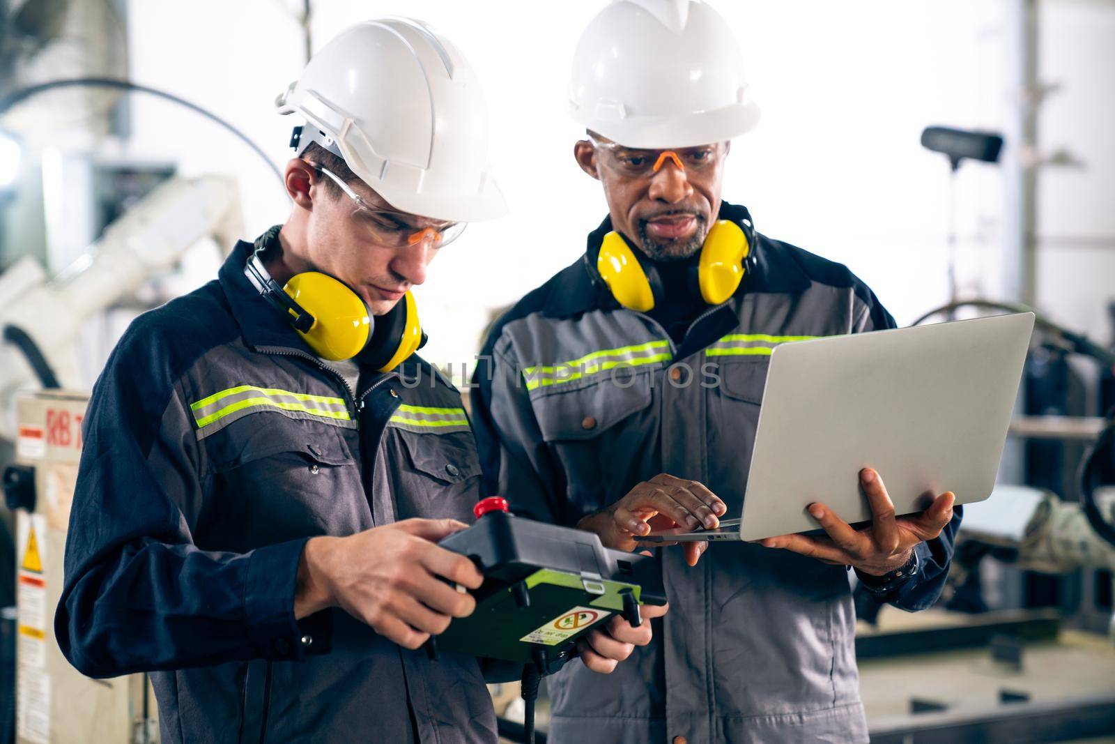 Group of factory job workers using adept machine equipment in a workshop by biancoblue