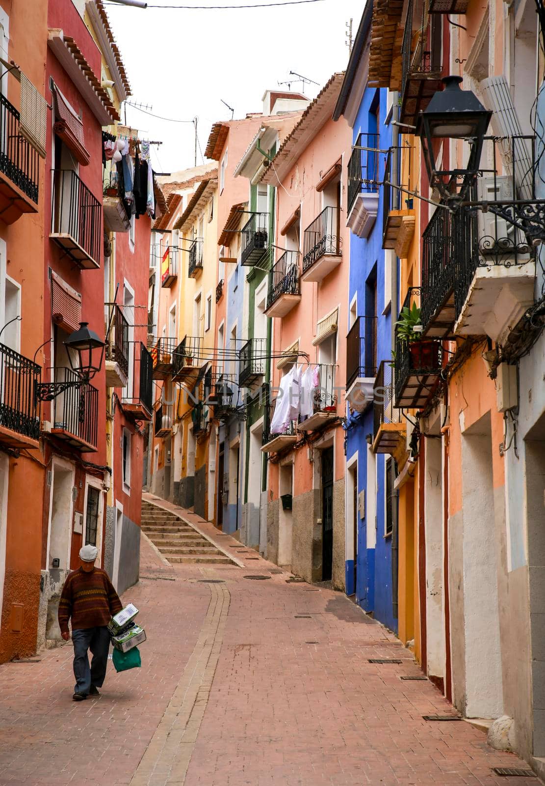 Villajoyosa, Alicante, Spain- April 22, 2022:Narrow cobbled street and beautiful colorful facades in Villajoyosa village, Alicante, Spain