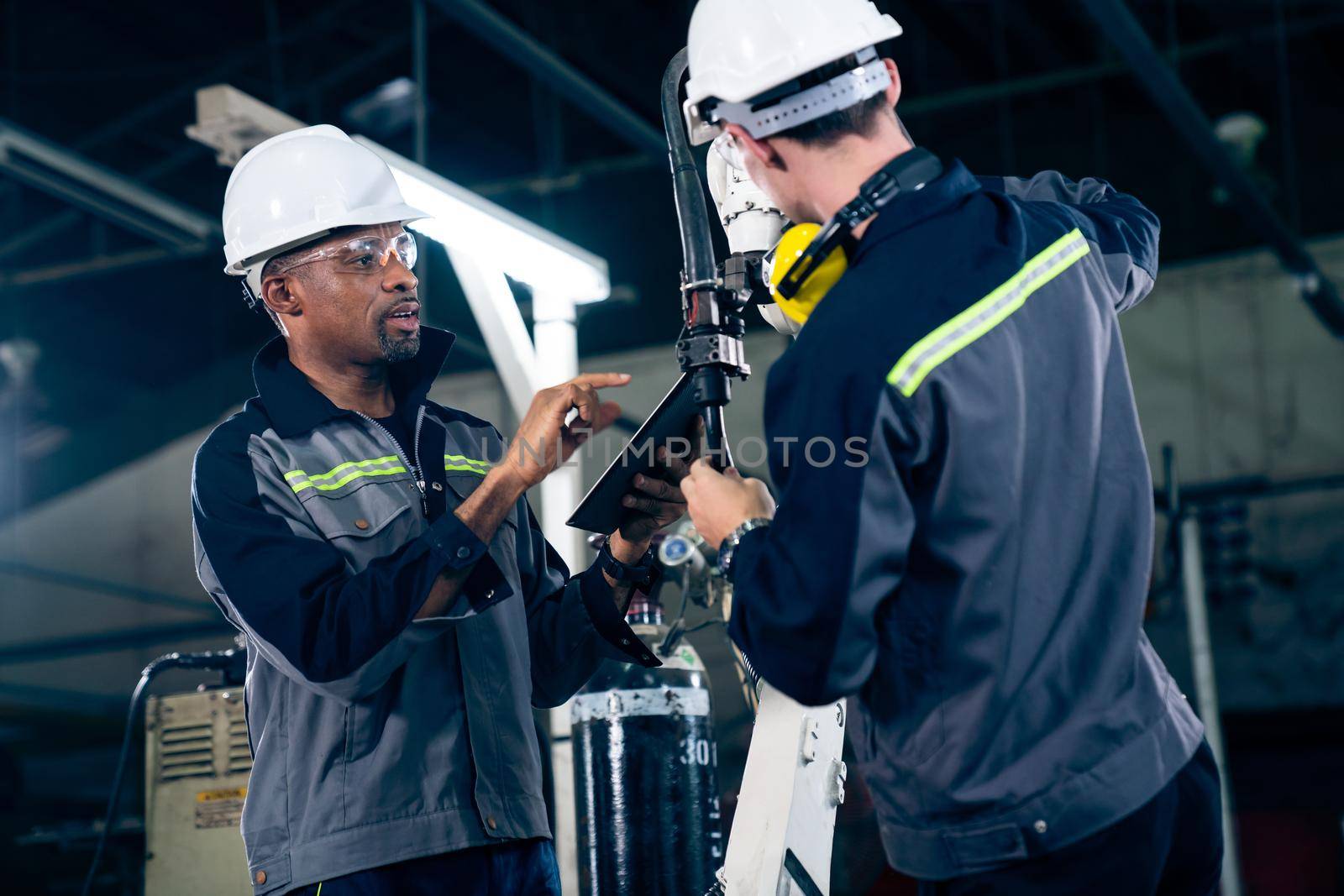 Factory workers working with adept robotic arm in a workshop . Industry robot programming software for automated manufacturing technology .