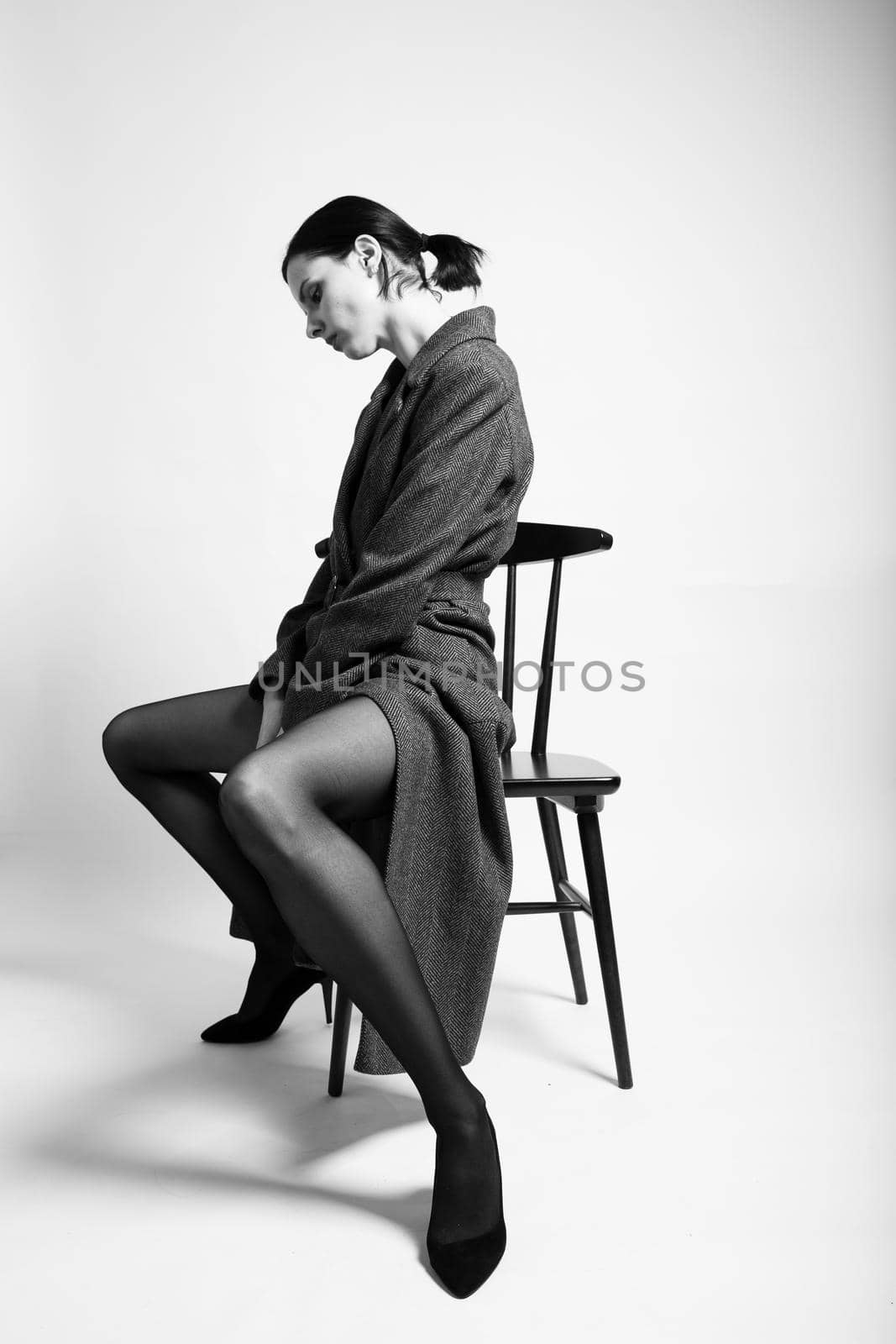 beautiful woman in a coat sits on a chair by shilovskaya