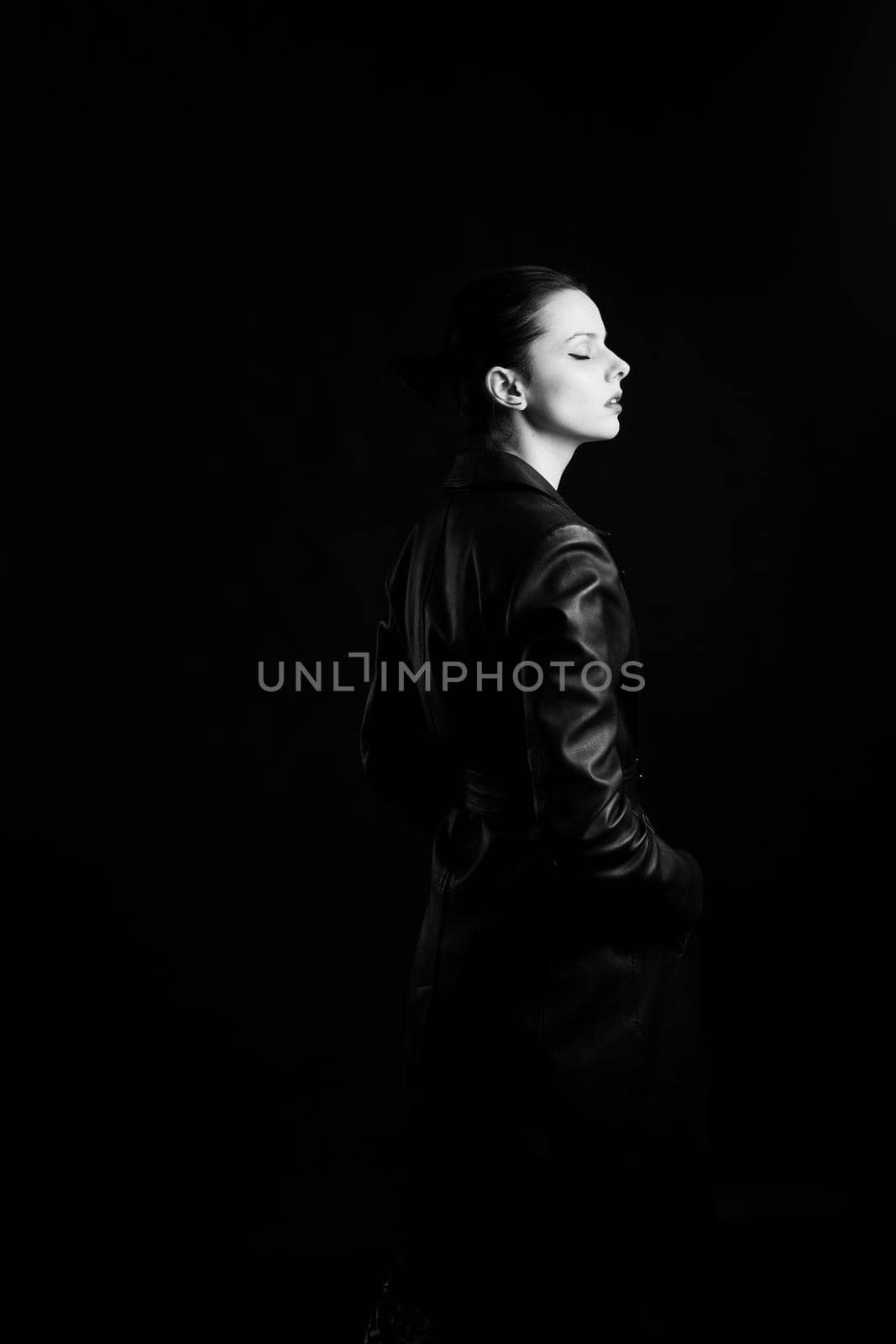 woman with closed eyes in leather coat and, black background. High quality photo