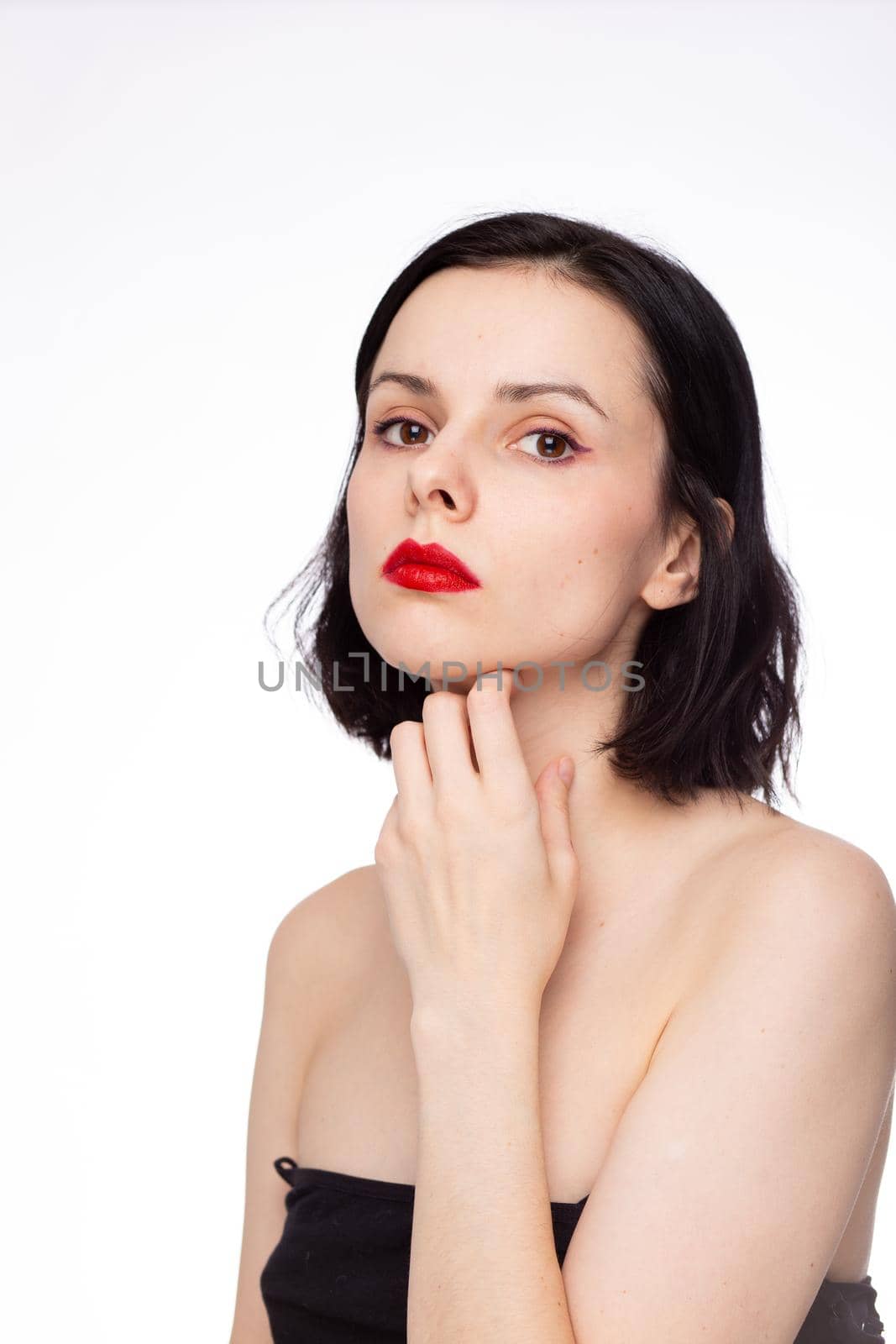 brunette woman with red lips in black top, white studio background. High quality photo