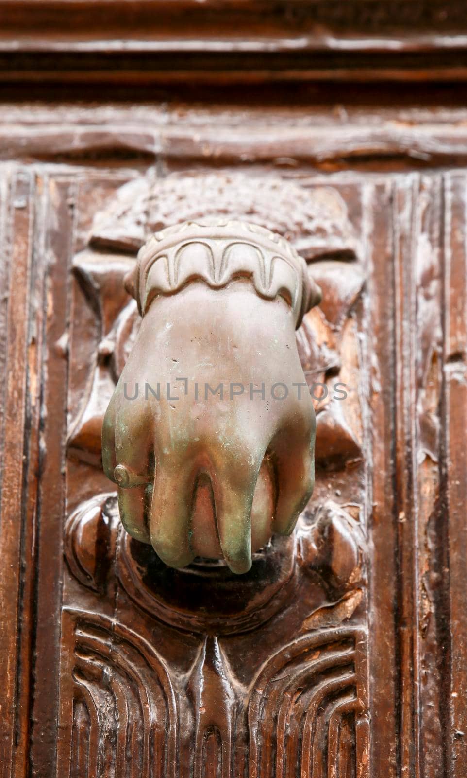 Golden doorknocker with hand shape on old brown wooden door in Villajoyosa, Alicante, Spain