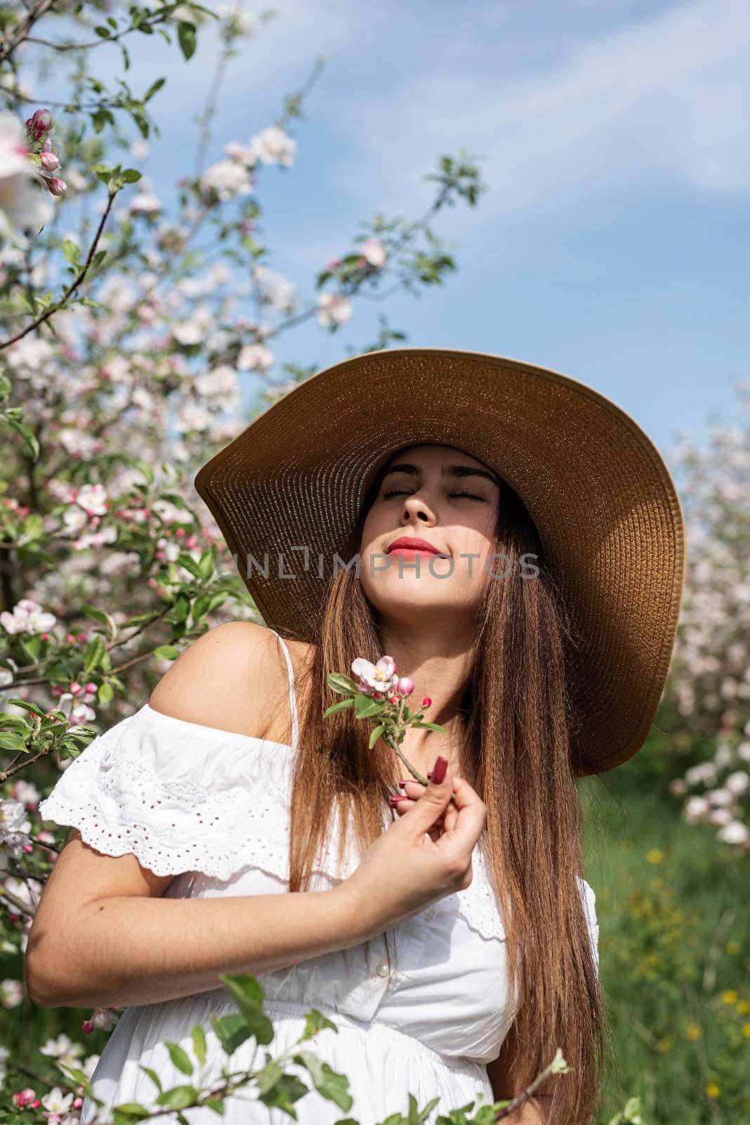 Spring concept. Nature. Portrait of young caucasian woman enjoying the flowering of an apple trees, walking in spring apple gardens