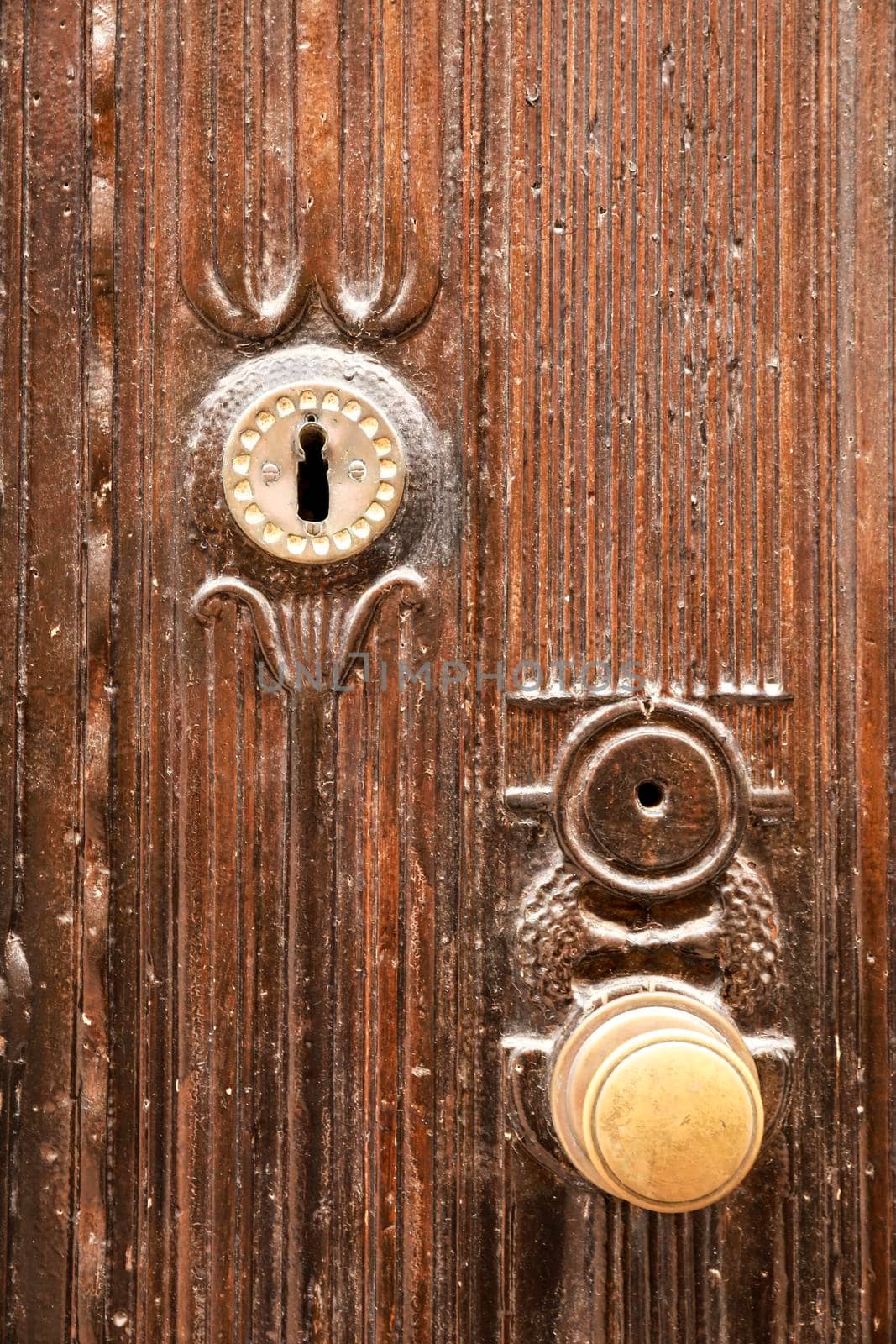 Golden doorknocker with modernist style on old brown wooden door in Villajoyosa, Alicante, Spain
