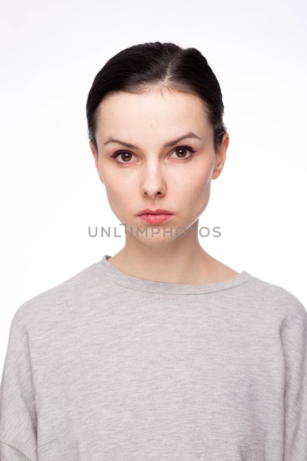 cute brunette woman with gray sweatshirt, white background. High quality photo