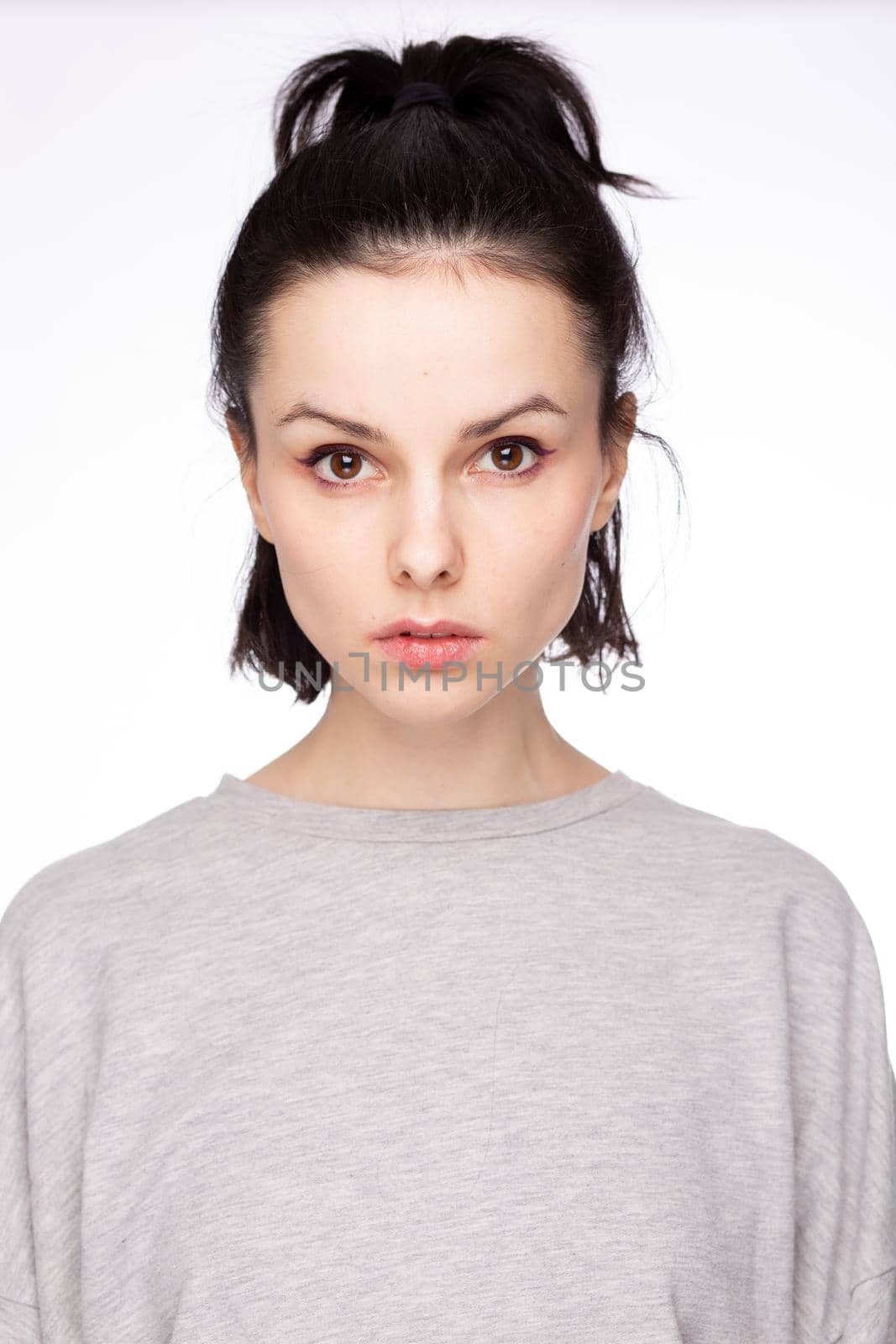 cute brunette woman with gray sweatshirt, white background. High quality photo