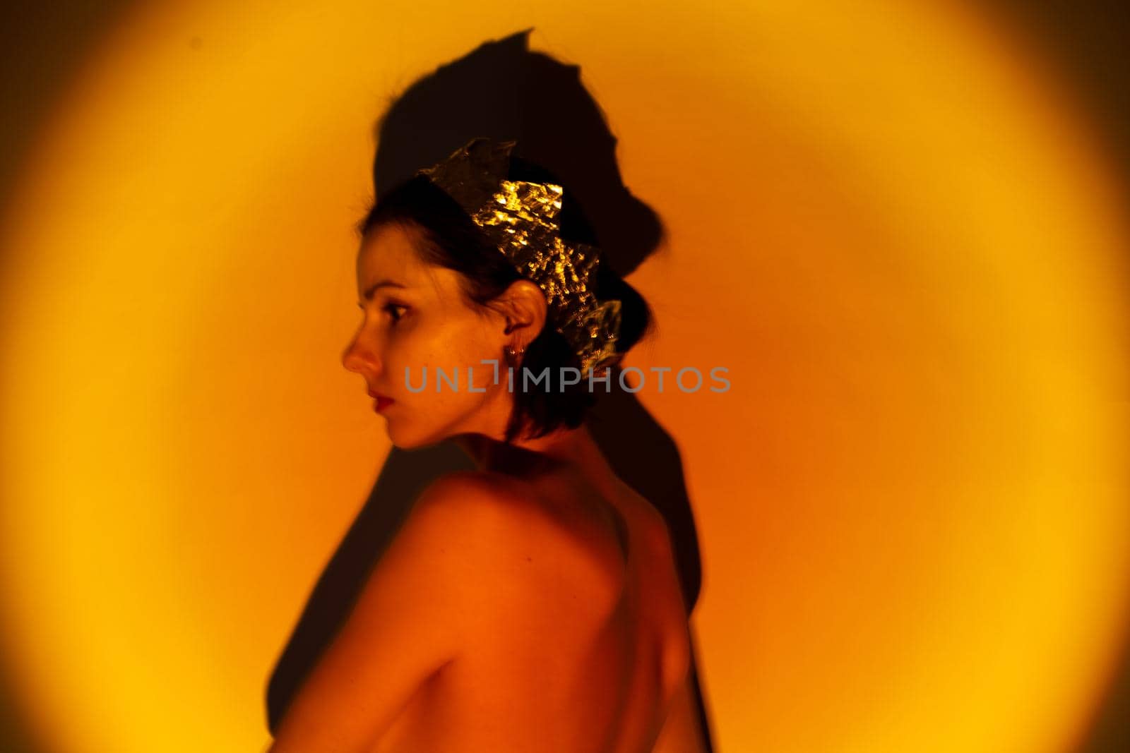 woman with a crown on her head in yellow light, art portrait. High quality photo