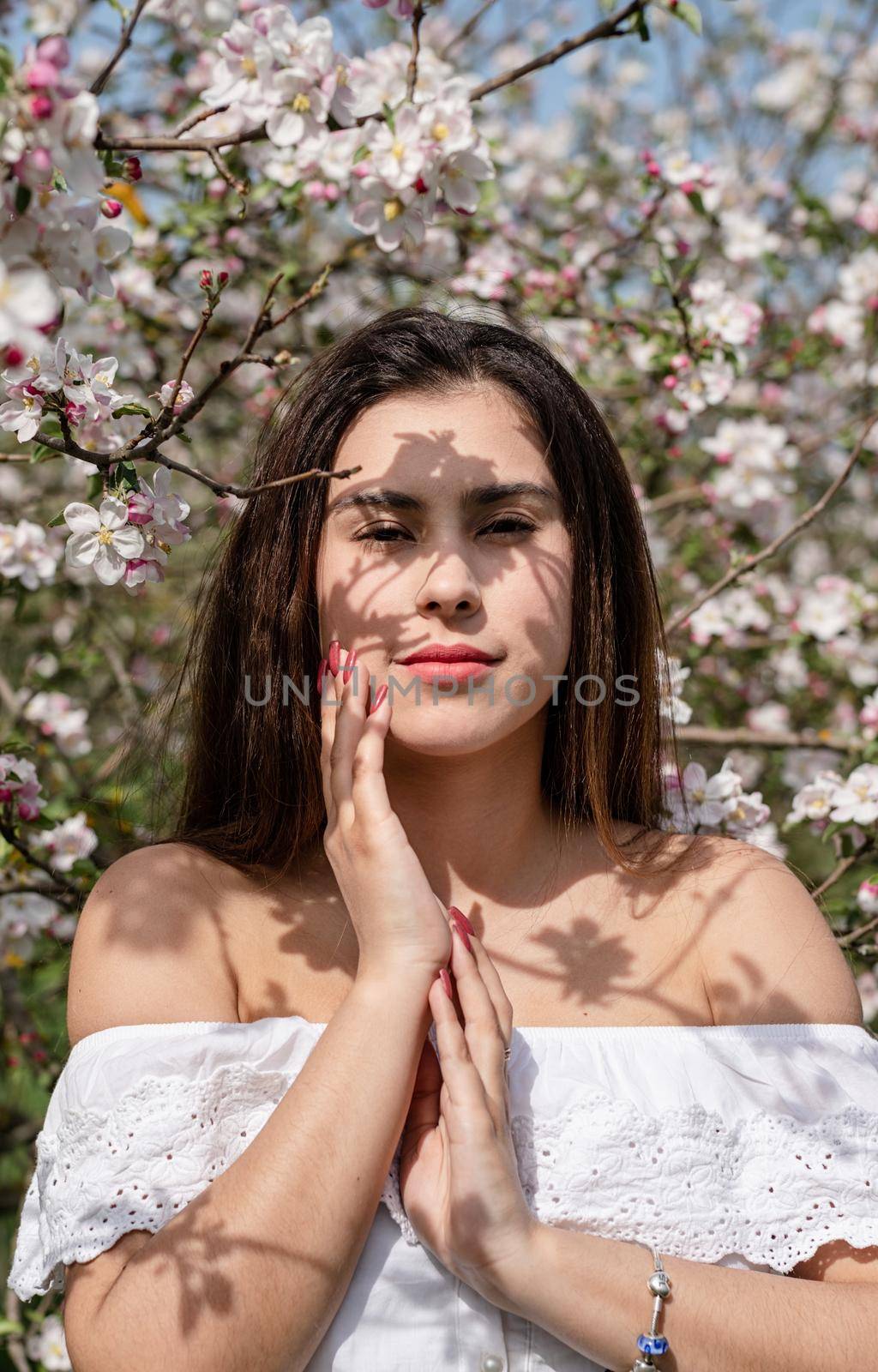 Young caucasian woman enjoying the flowering of an apple trees by Desperada