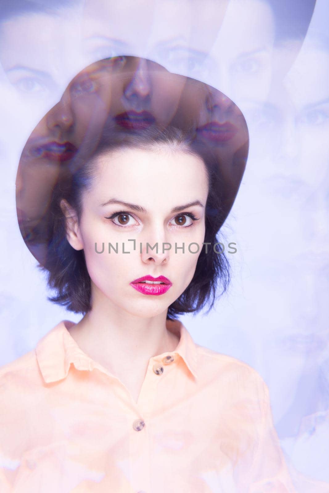 woman with pink lips in a hat on a blue background, art portrait. High quality photo