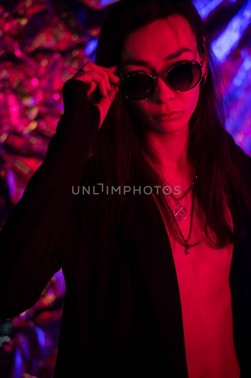 Portrait of a transgender model in sunglasses in a studio with neon lighting. by mrwed54
