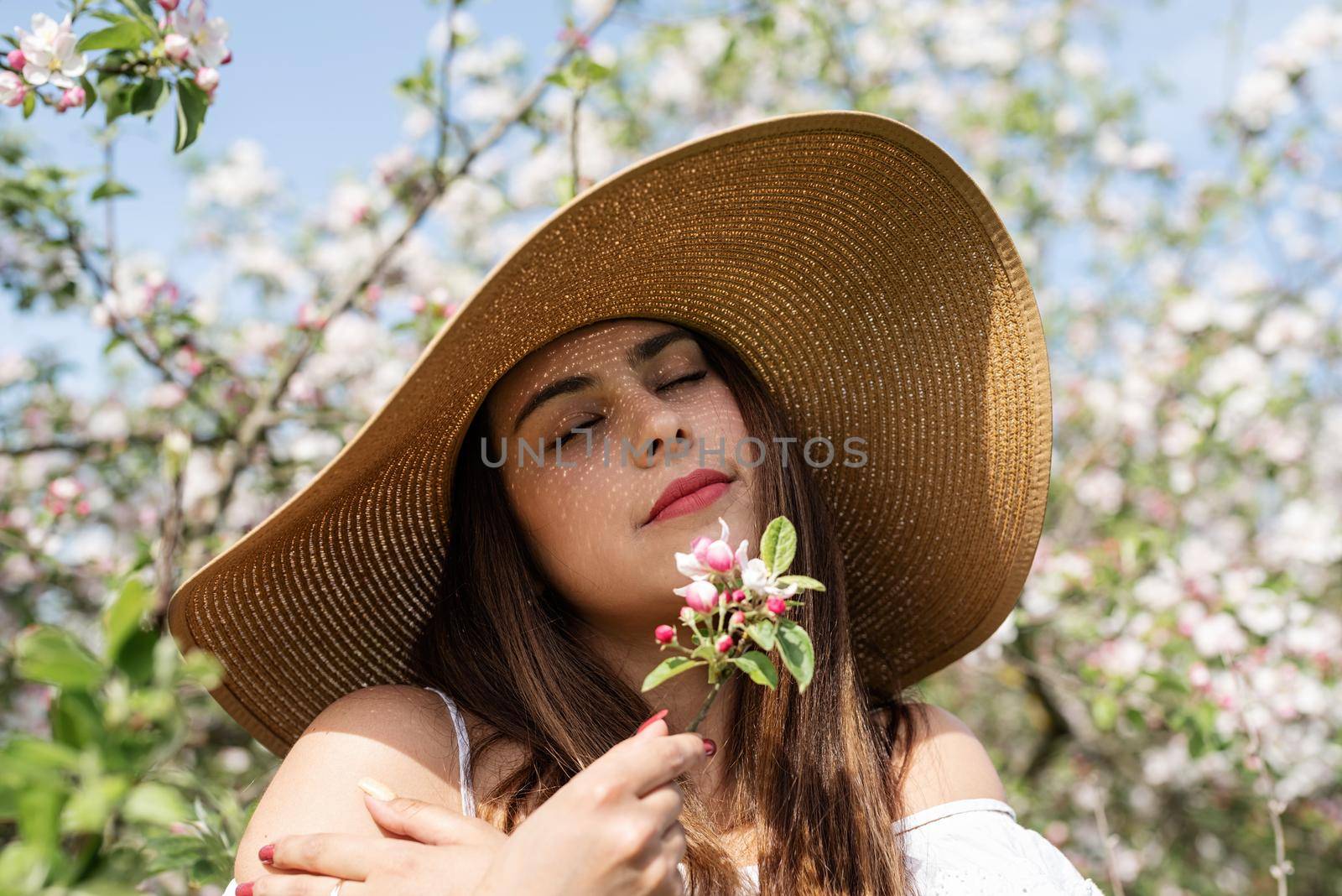 Young caucasian woman enjoying the flowering of an apple trees by Desperada