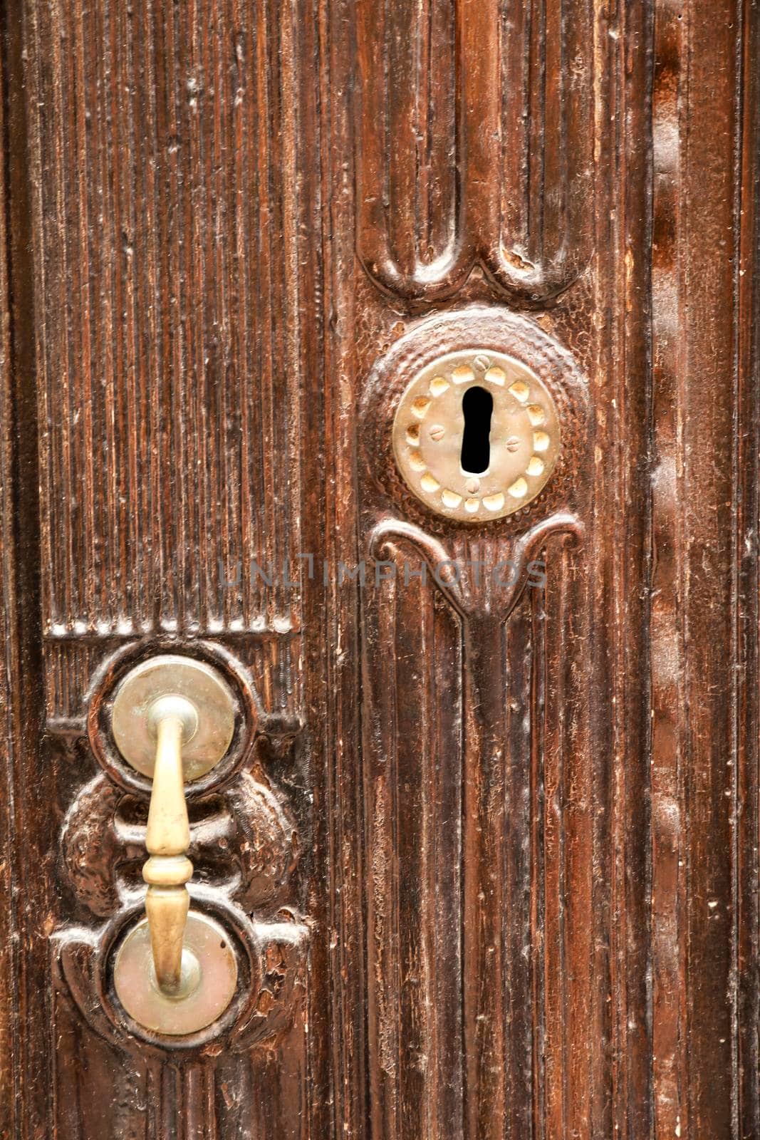 Golden doorknocker with modernist style on old wooden door by soniabonet