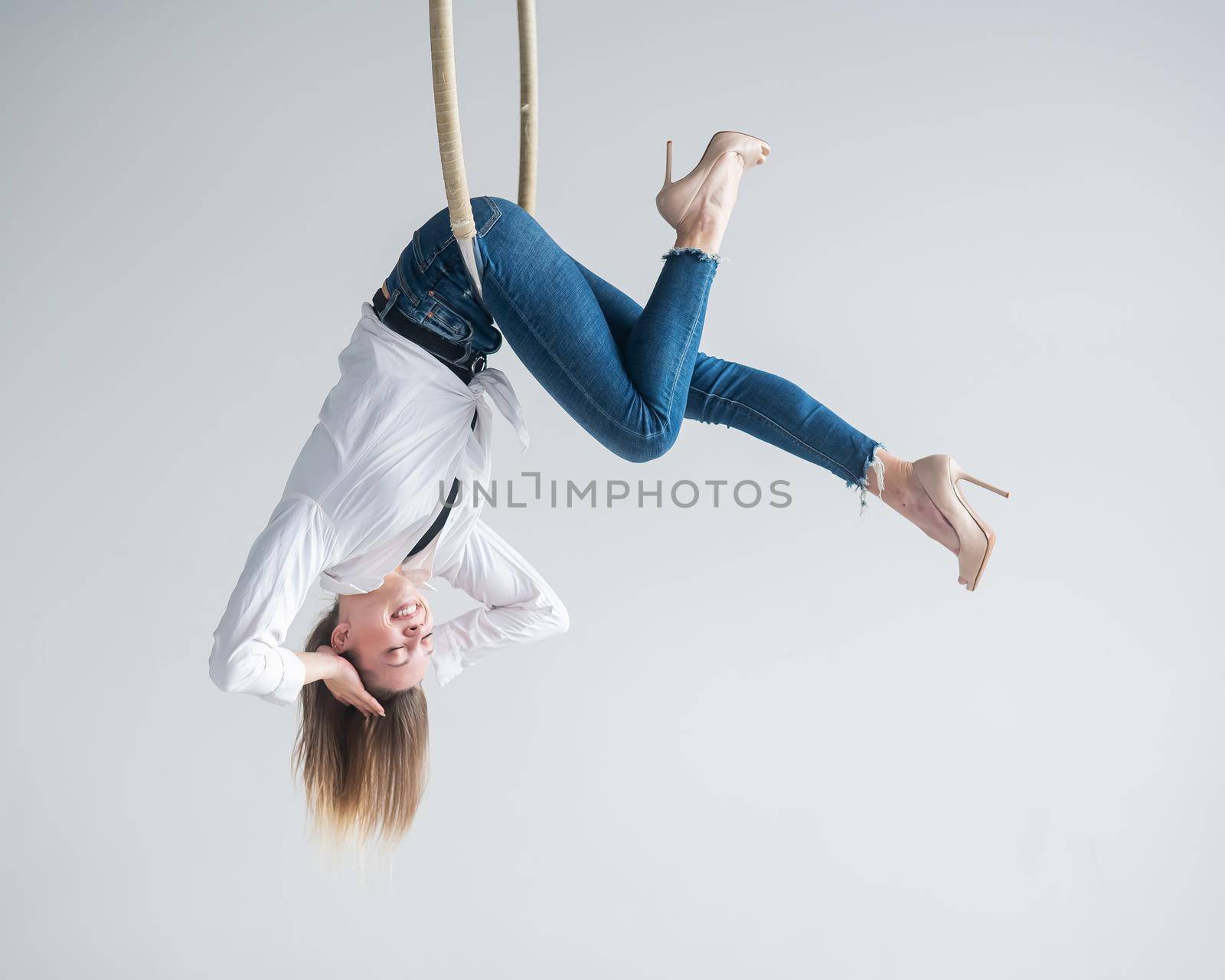 Caucasian woman in casual clothes on an aerial hoop