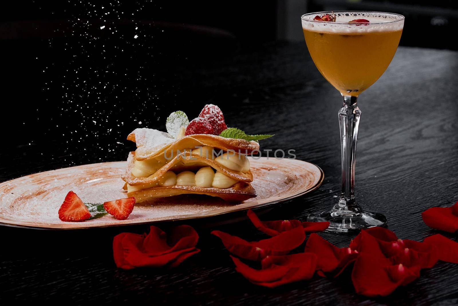 Sweet puff pastry dessert with strawberries aperitif glass with rose petals. High quality photo